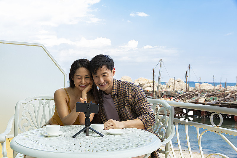 浪漫情侣在海边旅行度假酒店喝咖啡做直播图片素材