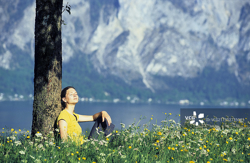在奥地利萨尔茨卡默古特湖区特劳恩湖的树下放松的女人图片素材