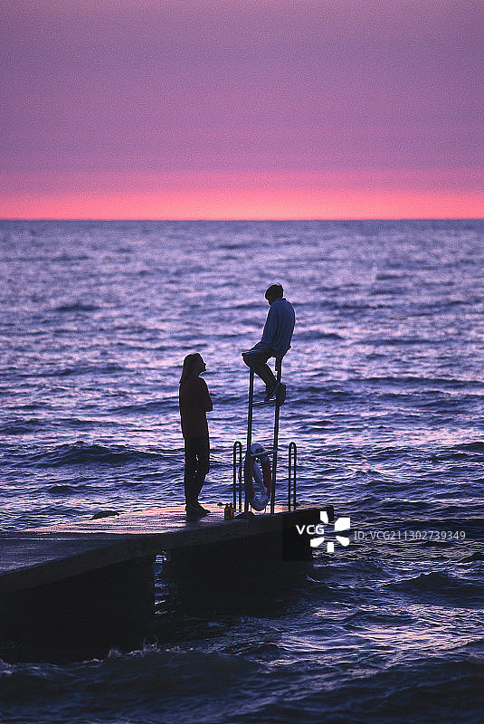 在瑞典哥特兰岛海边的码头上交谈的两个青少年图片素材