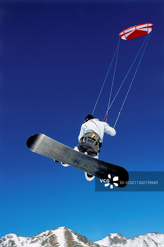 男人在雪地里玩风筝滑雪跳跃，位于奥地利蒂罗尔州图片素材