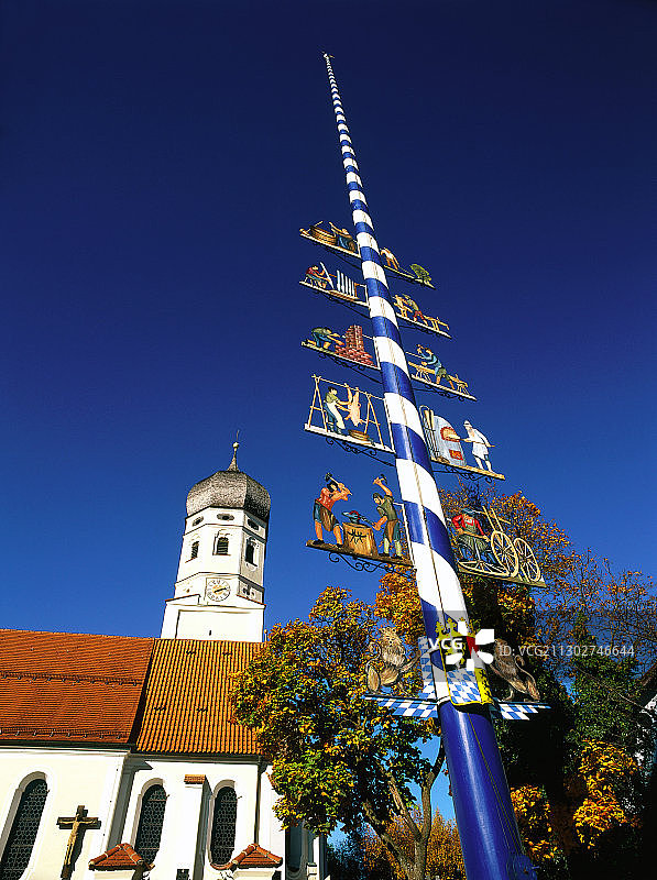 德国上巴伐利亚州埃尔林村的五月柱和乡村教堂的低角度视图图片素材
