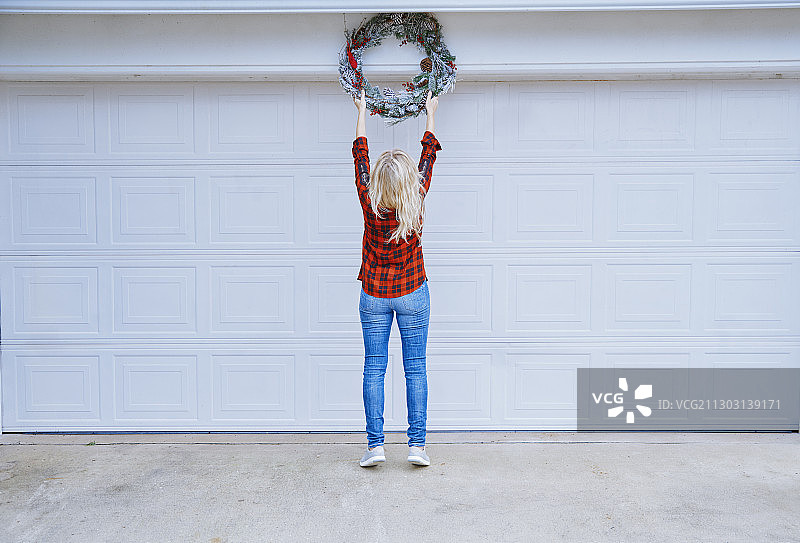 女人用圣诞花环装饰她的车库图片素材