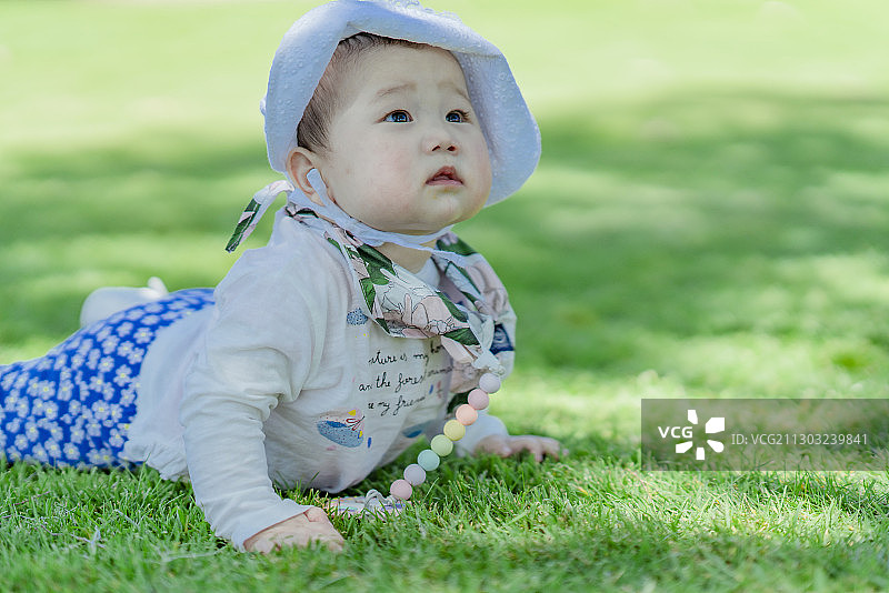 趴在草坪上玩乐的女婴图片素材