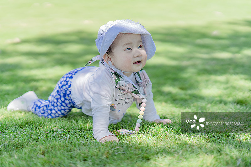 趴在草坪上玩乐的女婴图片素材