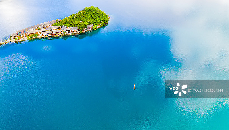 航拍泸沽湖，蓝天白云倒映在湛蓝的湖水，一条猪槽船划破湖面图片素材