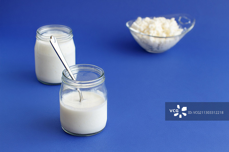 蓝色背景下玻璃罐中的牛奶特写图片素材