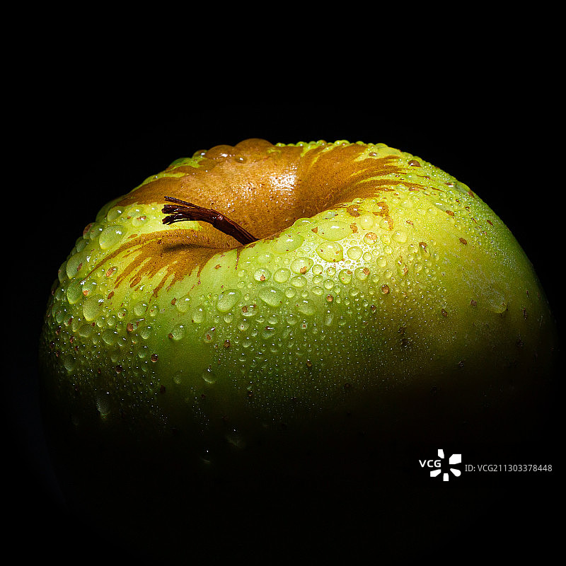 黑色背景下的潮湿青苹果特写图片素材