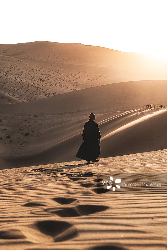 鸣沙山夕阳下僧人在沙山上行进图片素材