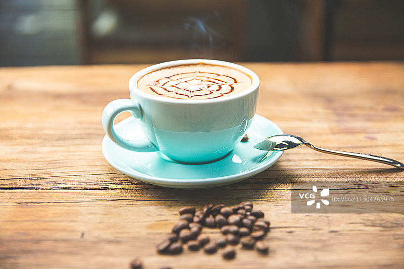一杯放在木头桌子上的卡布奇诺拿铁美式咖啡与咖啡勺玫瑰图片素材