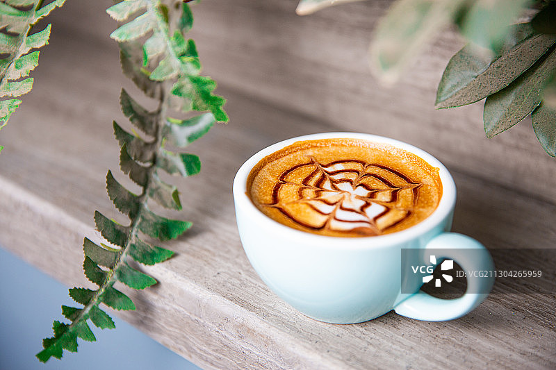 一杯放在木头桌子上的卡布奇诺拿铁美式咖啡与咖啡勺玫瑰图片素材