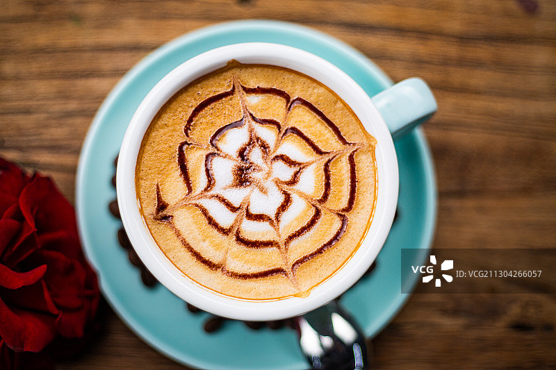 一杯放在木头桌子上的卡布奇诺拿铁美式咖啡与咖啡勺玫瑰图片素材