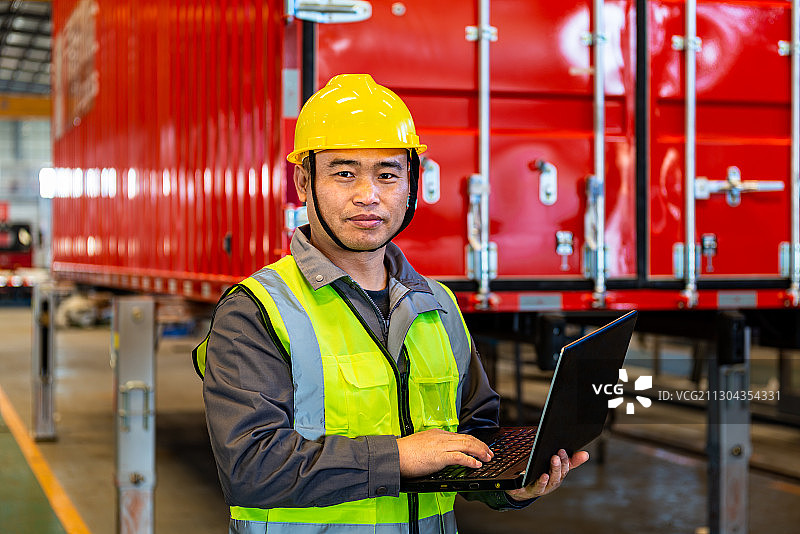 厂房里一名戴着安全帽拿着笔记本电脑的专业技术人员图片素材
