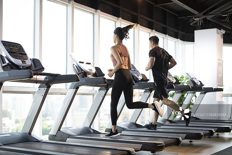 年轻情侣在健身房跑步图片素材