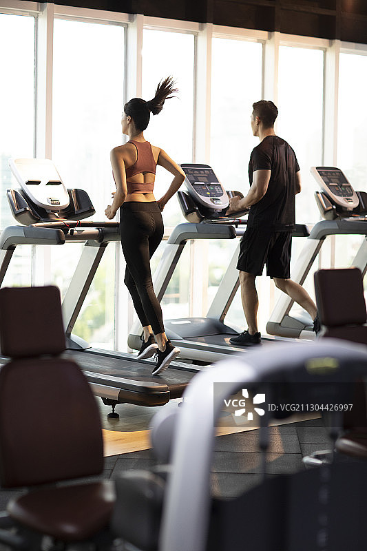 年轻情侣在健身房跑步图片素材