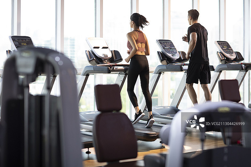 年轻情侣在健身房跑步图片素材