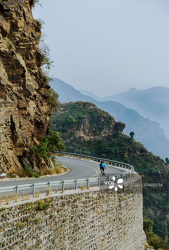 白昼山崖山峰道路骑行者背影图片素材