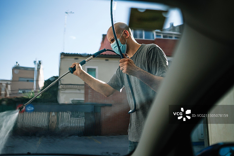 在西班牙用高压清洗机洗车的白人男子图片素材