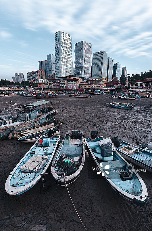 城市的变迁发展下，曾经的小渔村与现代的商业建筑显得格格不入图片素材