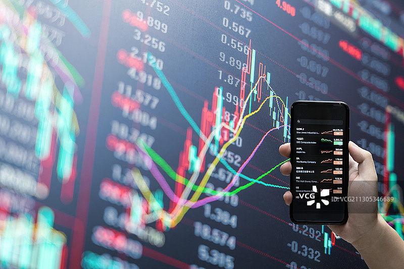 拿着手机看股票和股票证券交易数据分析图片素材