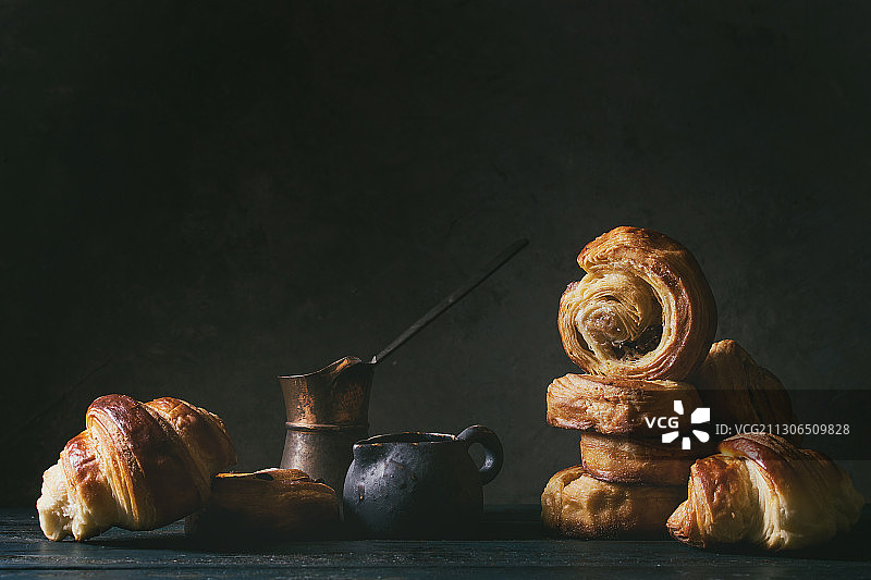 黑色背景下，桌子上放着带厨房用具的酥皮点心特写图片素材