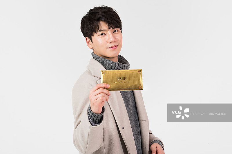 身穿冬装微笑手持礼券的男人图片素材