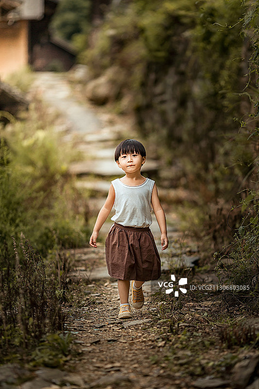 一个穿着背心的小男孩从乡村小路上走来图片素材