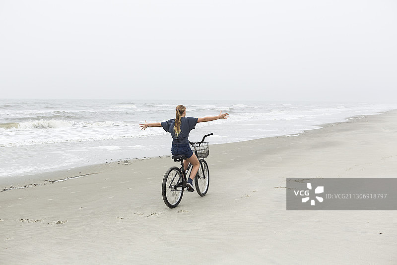 少女在佐治亚州圣西蒙斯岛海滩骑自行车图片素材