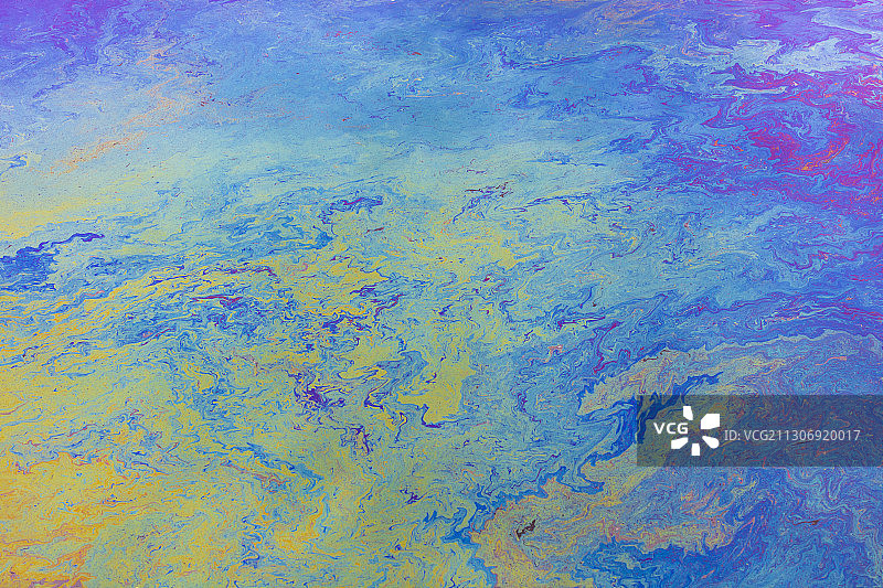 海洋水面上洒落的柴油燃料，蓝色和黄色图案特写图片素材