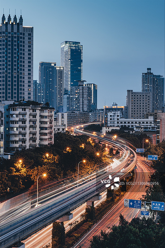 傍晚日落后轻轨在城市森林高楼大厦之间划出优美的车轨曲线图片素材