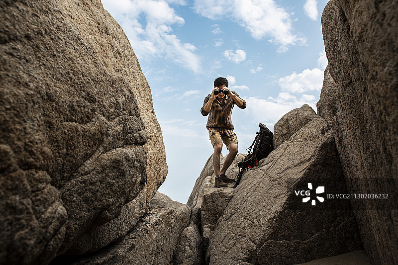 青年男子在户外拿着望远镜攀岩探险图片素材