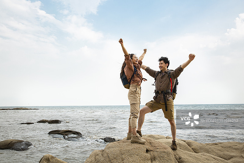 年轻情侣在户外海边做攀岩运动欢呼图片素材