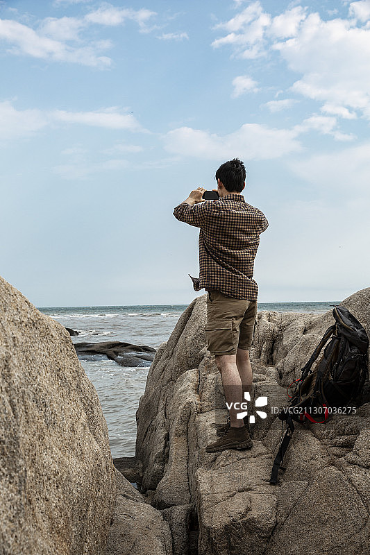 青年男子在户外攀岩探险拿着手机拍照图片素材