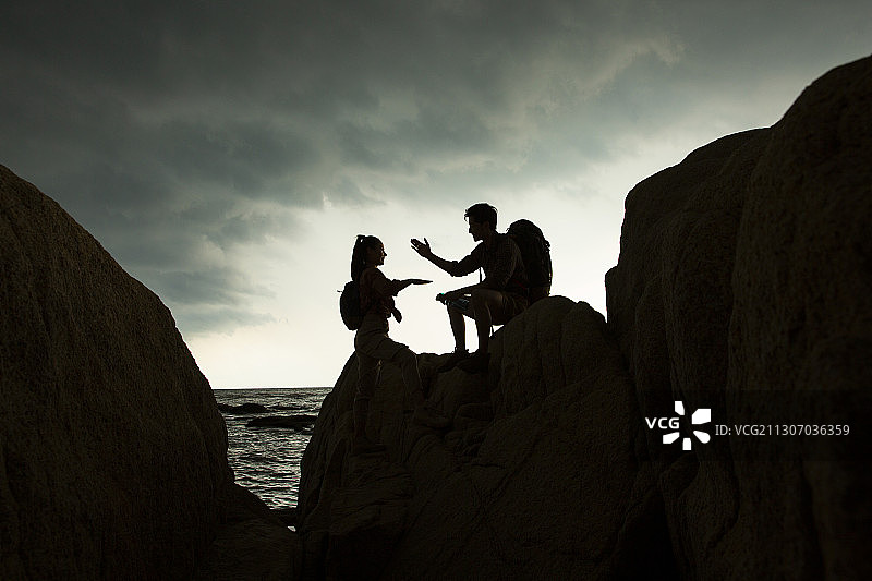 年轻情侣海边户外做攀岩运动击掌图片素材