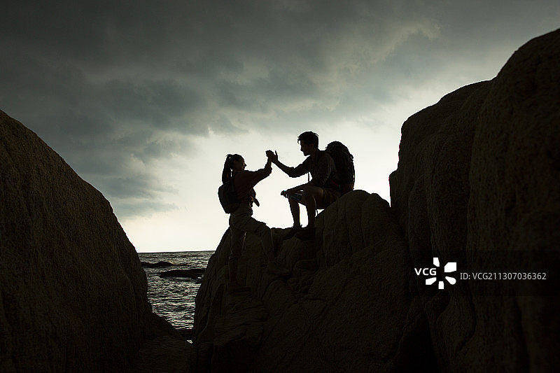 年轻情侣海边户外做攀岩运动击掌图片素材