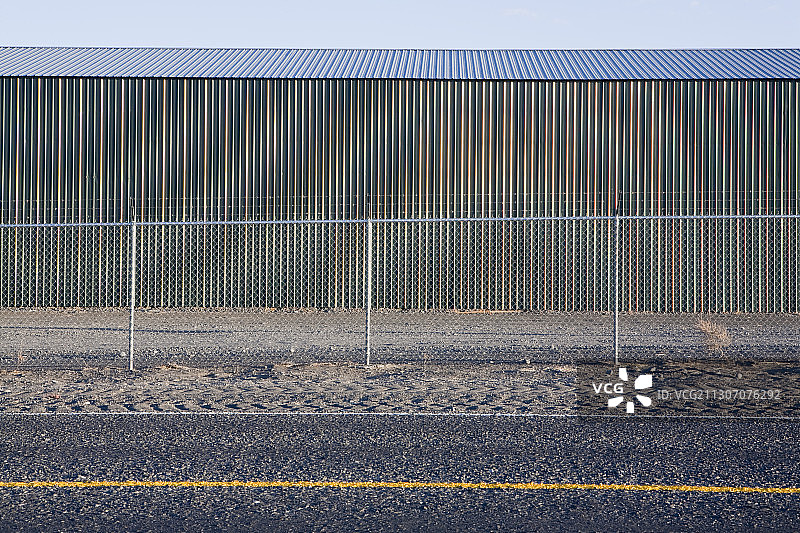 高速公路旁的瓦楞铁皮建筑与围栏图片素材