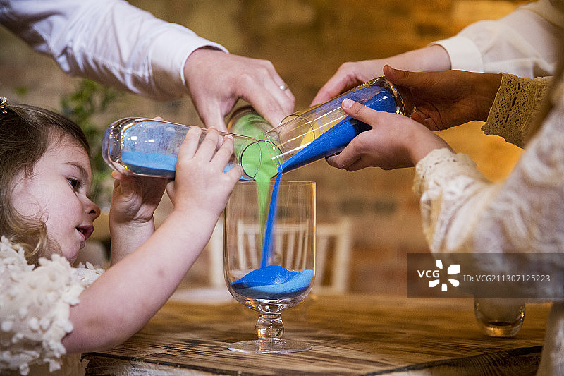 家人在历史悠久的谷仓的命名仪式上将彩色沙子倒入玻璃罐中图片素材