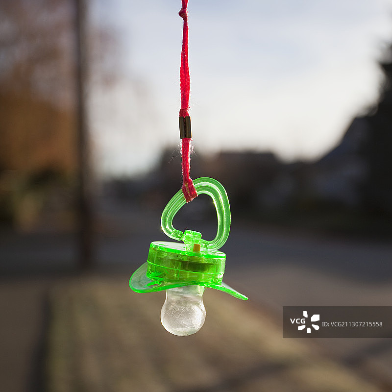 橙色挂绳上的绿色塑料婴儿奶嘴图片素材