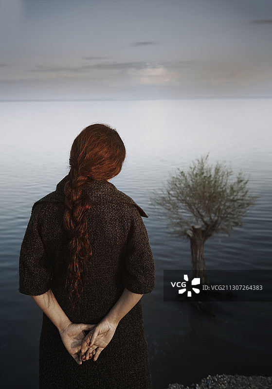 沉思的女人凝视水中的树图片素材