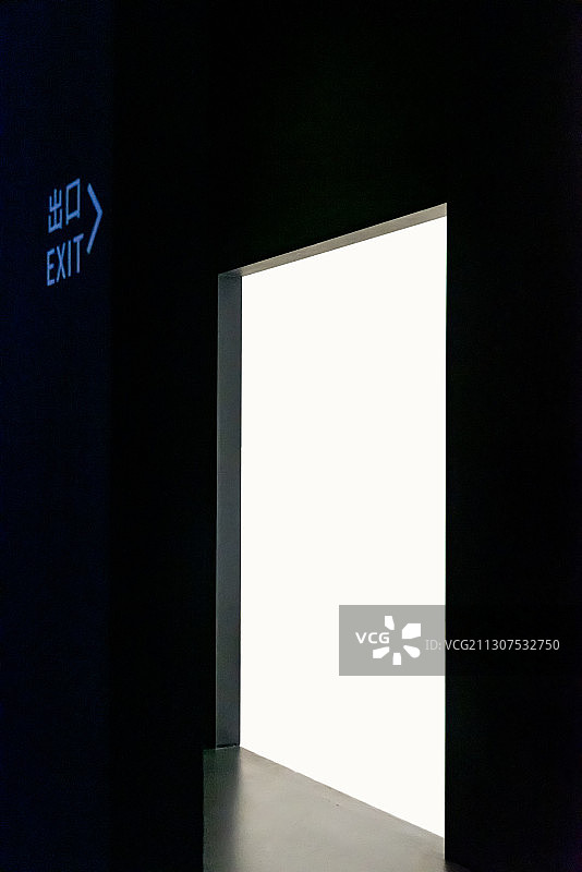 黑暗的房间里，幽暗的标志指向出口，出口外一片光明图片素材