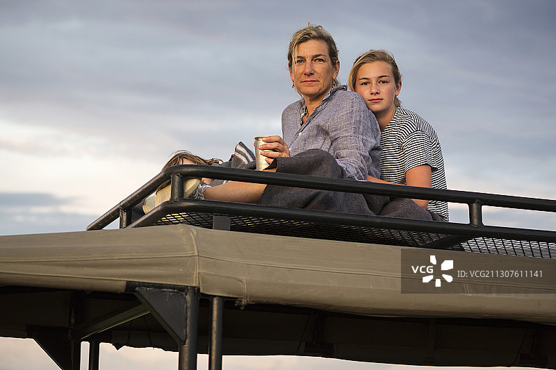 母亲和十几岁的女儿站在游猎车顶上眺望远方图片素材