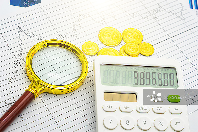 金融经济图表上的计算器、放大镜和硬币图片素材