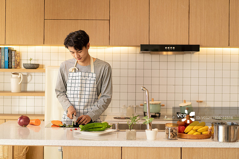 在温馨的厨房里切菜的年轻男人图片素材