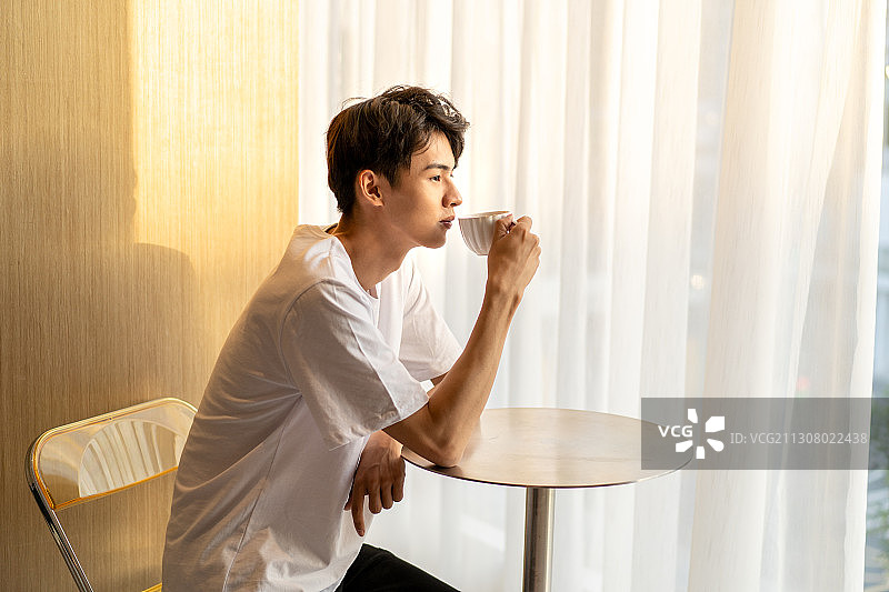 在咖啡店角落享受咖啡的年轻男士图片素材