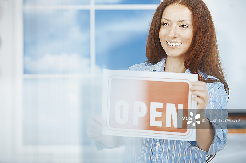 在新购物场所拿着“营业中”标牌的女人图片素材