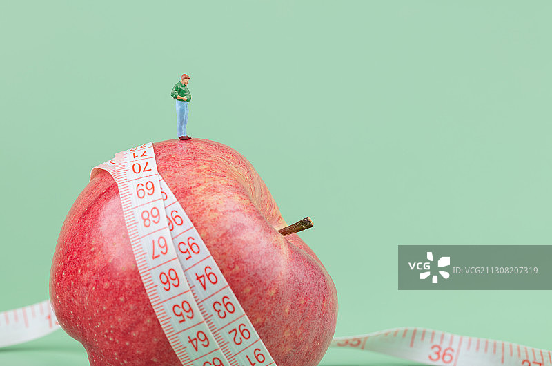 卷尺苹果上的一个大肚子大腰围男性胖子图片素材