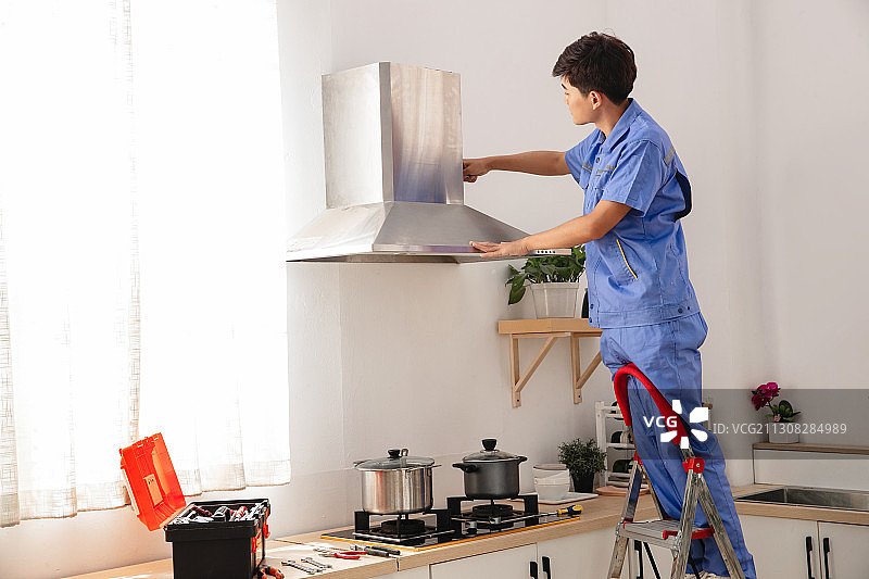 青年维修工修理油烟机图片素材