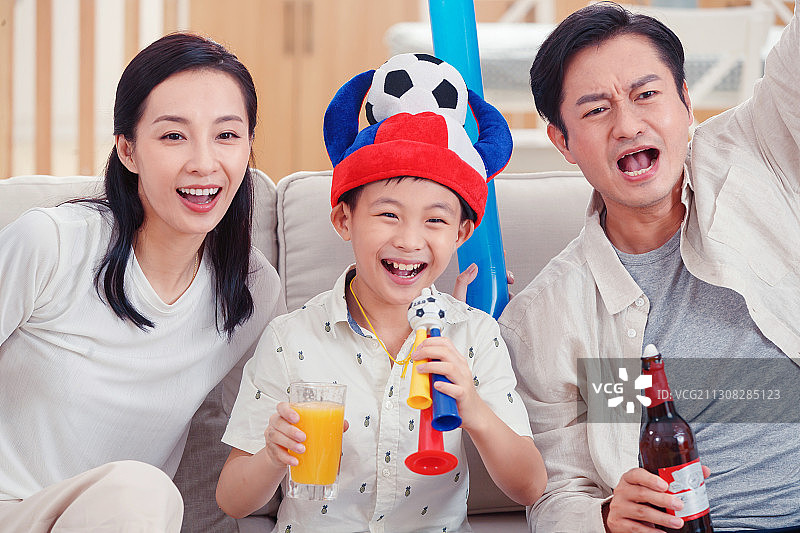 快乐的一家三口在家看球赛图片素材