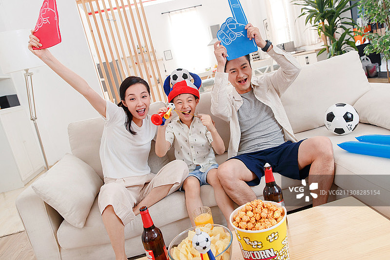快乐的一家三口在家看球赛图片素材