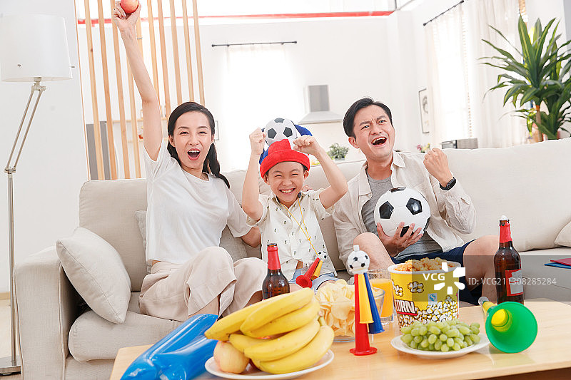 快乐的一家三口在家看球赛图片素材