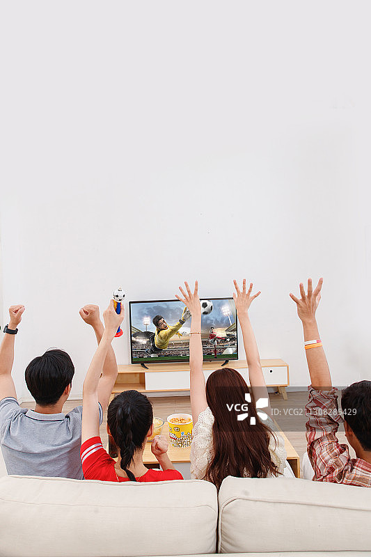 快乐的青年朋友在家看球赛图片素材